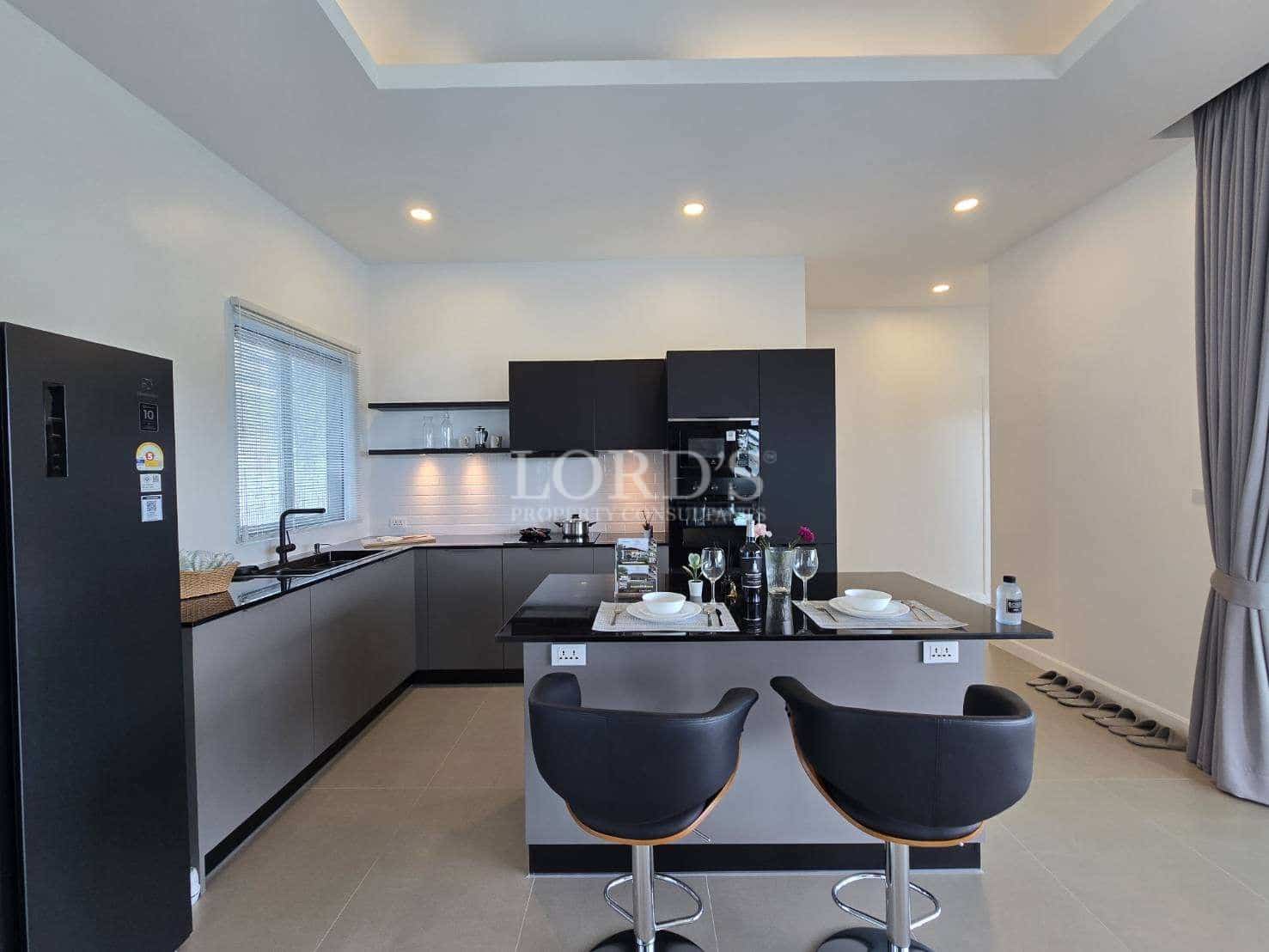 Modern minimalist kitchen with black cabinets, island seating, and built-in appliances.