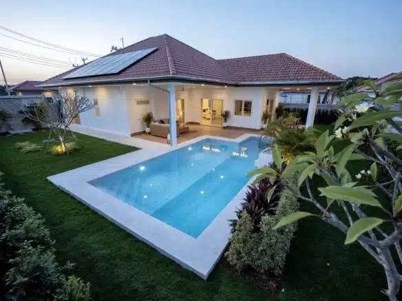 Luxury single-story villa with private swimming pool and landscaped garden at sunset.