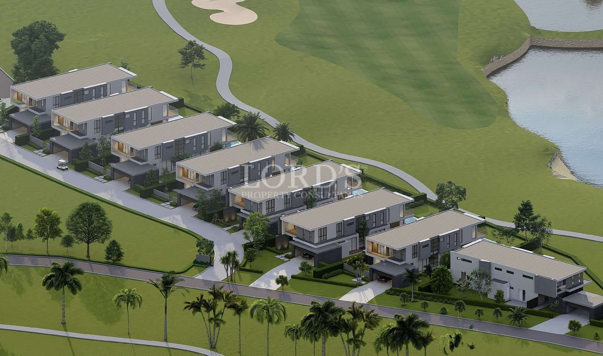 Aerial view of modern luxury villas arranged along a landscaped road beside a golf course and water features.