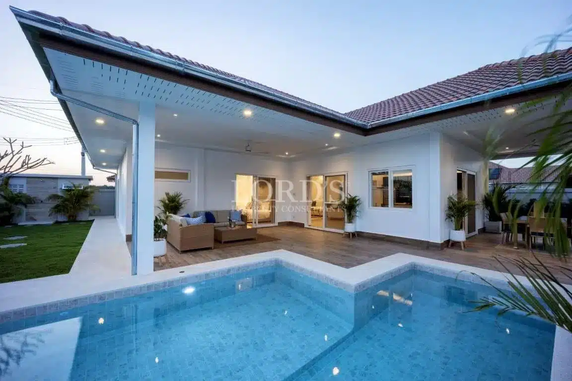Modern single-story villa with covered patio and private swimming pool at dusk.