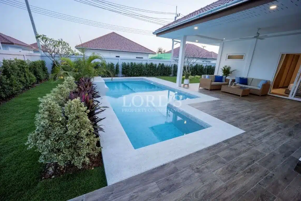 Private swimming pool with landscaped garden and covered patio seating area in a modern single-story villa.