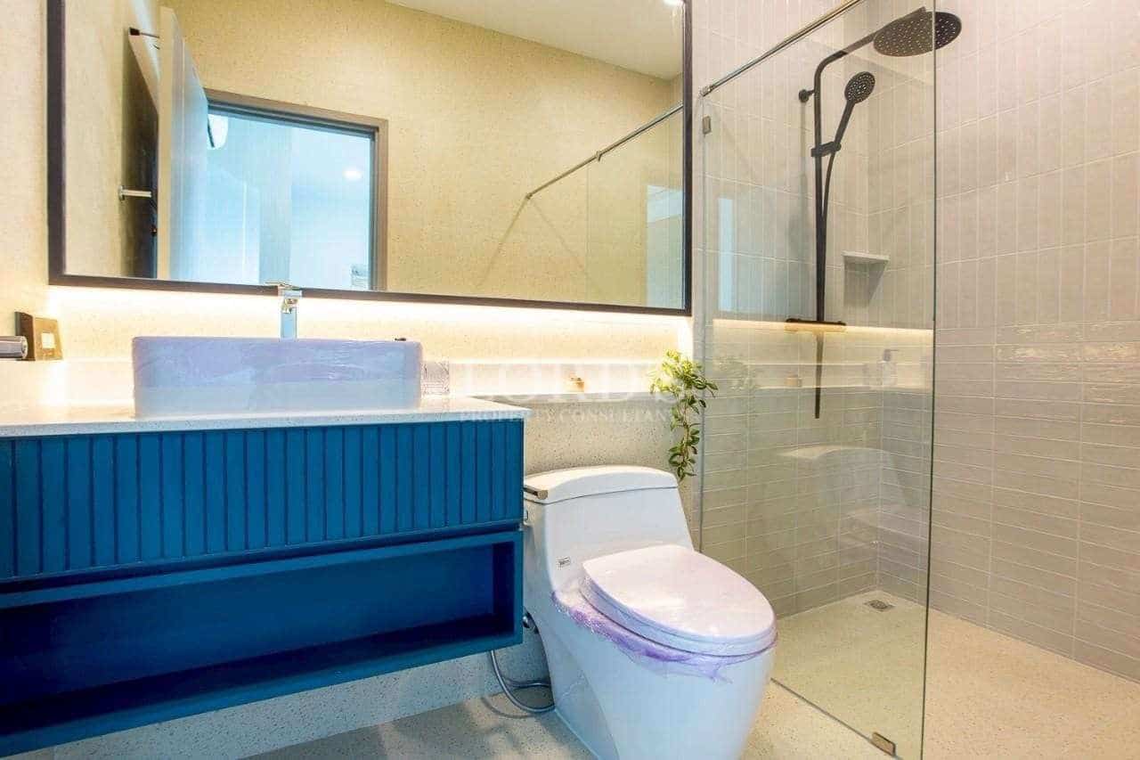 Modern bathroom with walk-in glass shower, rain showerhead, and blue vanity unit.