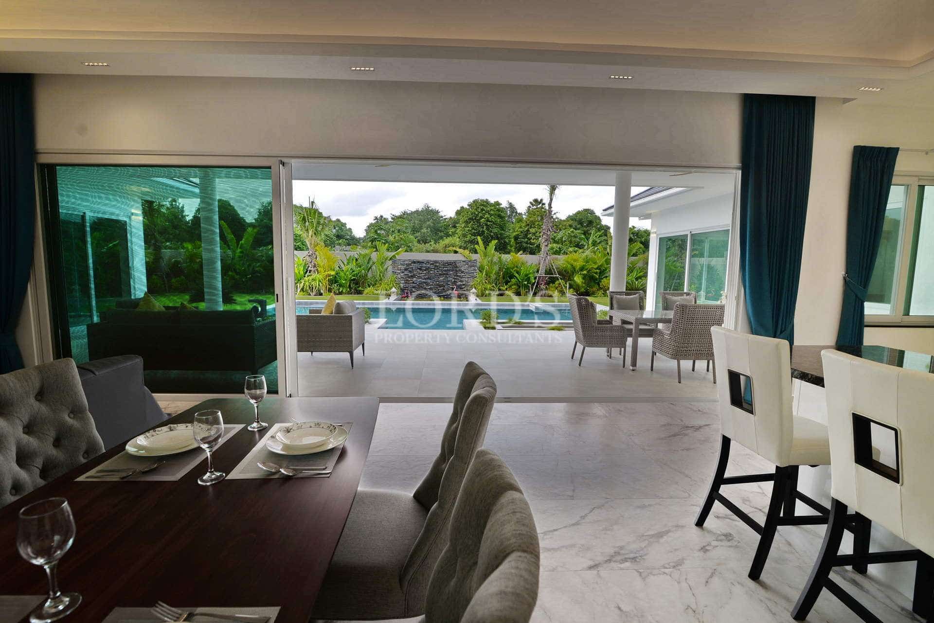 Modern open-plan dining and living area with sliding glass doors opening to a covered patio and private pool.