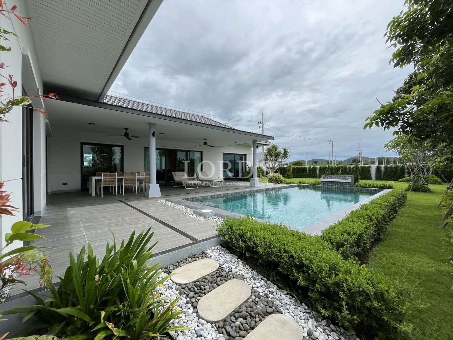 Private swimming pool with covered patio, outdoor dining area, and landscaped garden.