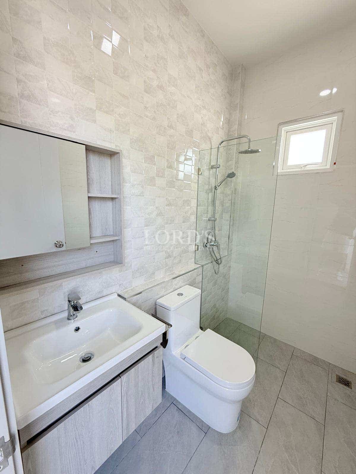 Modern minimalist bathroom with walk-in glass shower, wall-mounted vanity, and neutral tile design.