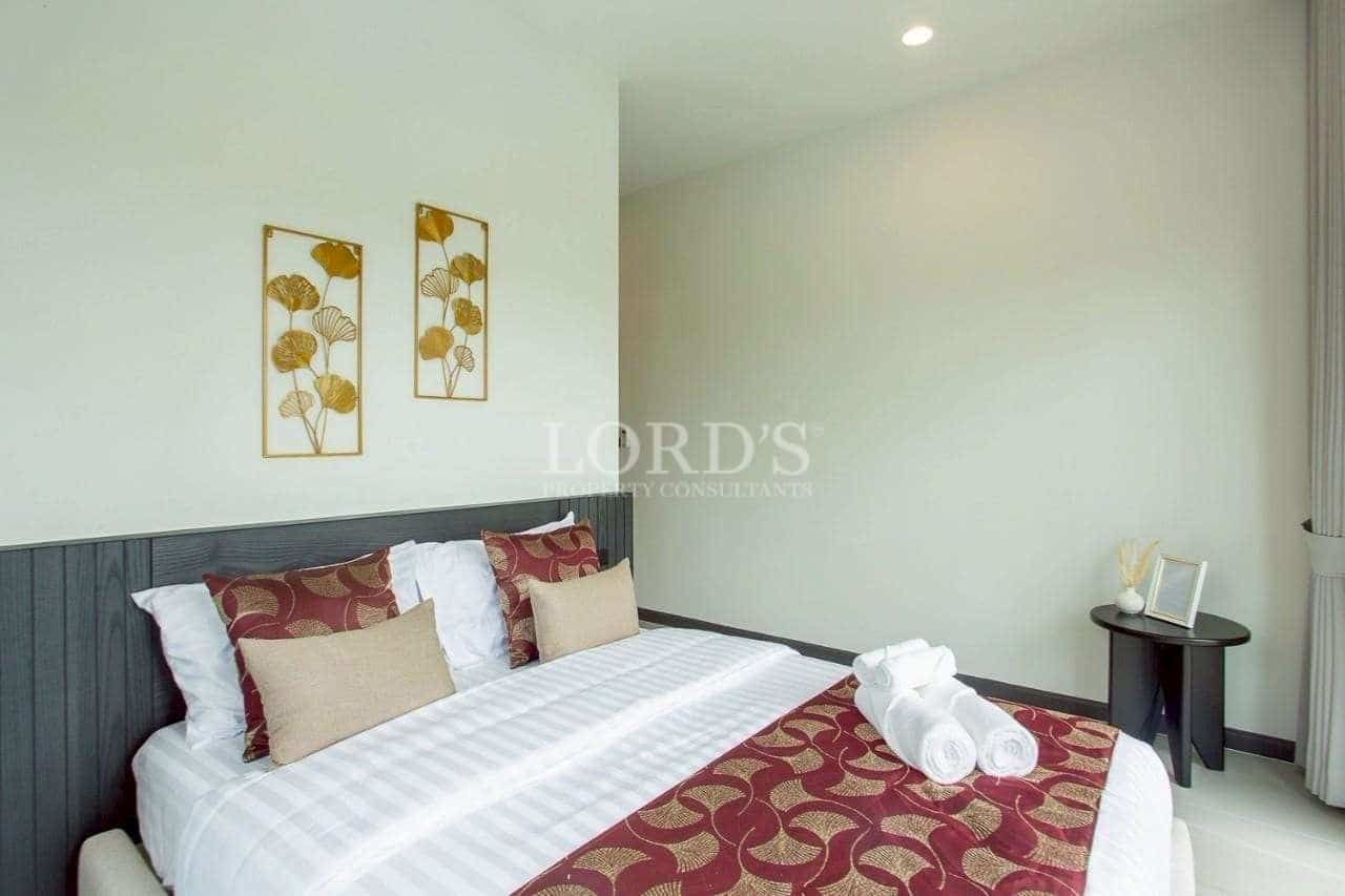 Modern bedroom with neutral walls, patterned bedding, and elegant gold wall art.