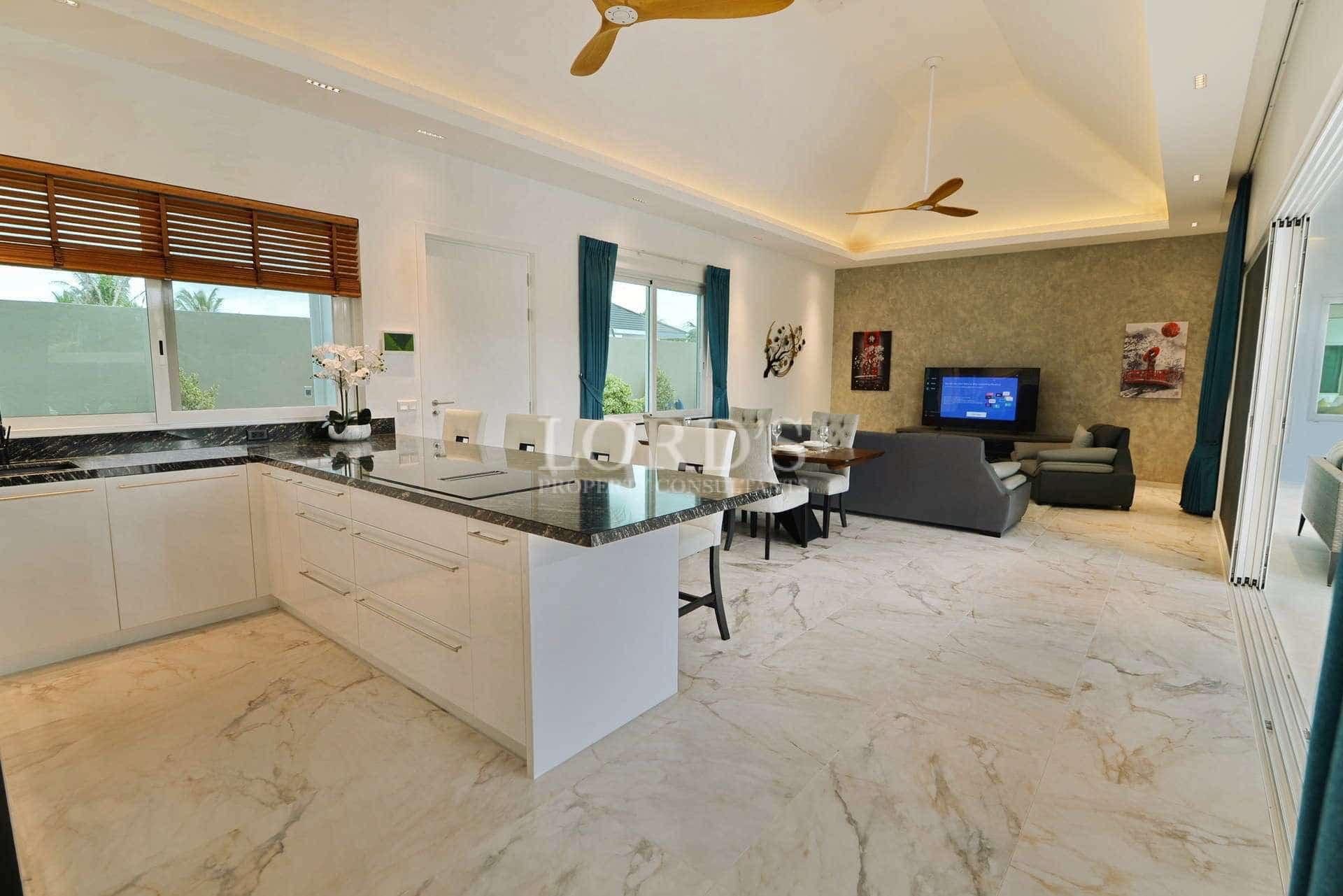 Open-plan modern kitchen and living area with marble flooring, island countertop, and contemporary furnishings.