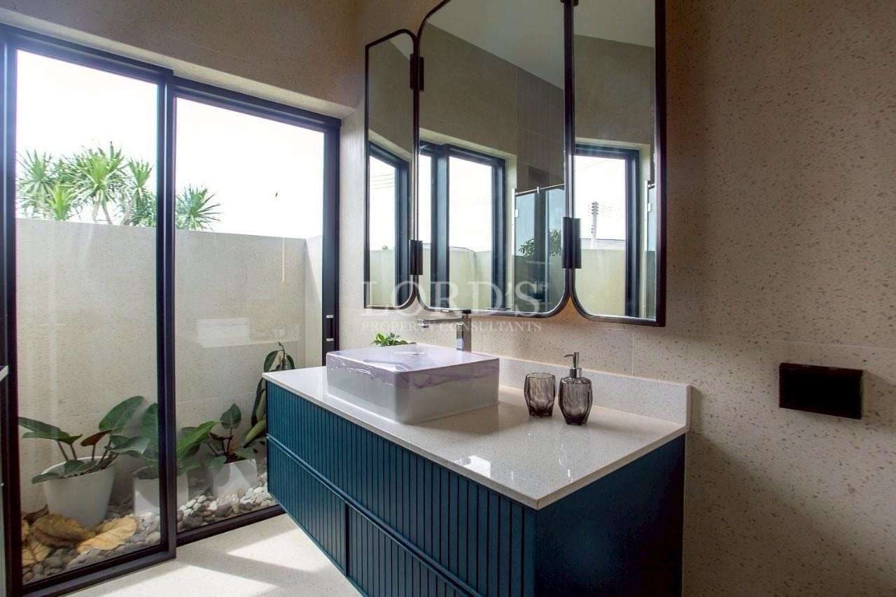 Modern bathroom vanity with stone countertop, vessel sink, black-framed mirror, and indoor garden view.