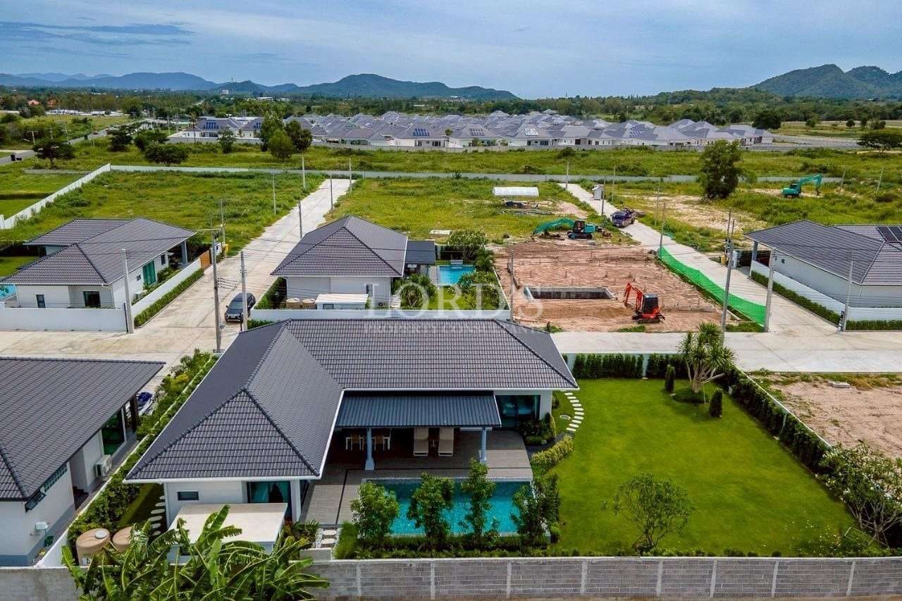 Aerial view of a modern residential villa community with landscaped homes and mountain backdrop.