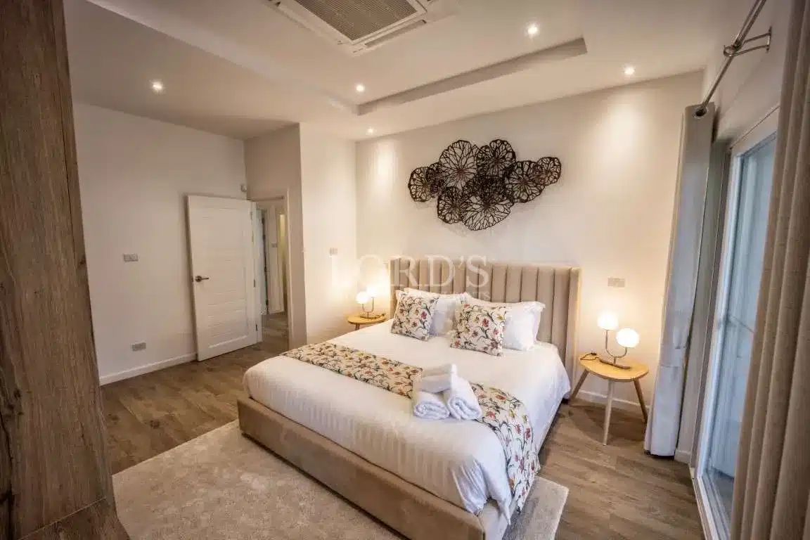 Elegant modern bedroom with upholstered bed, decorative wall art, wooden flooring, and soft ambient lighting.