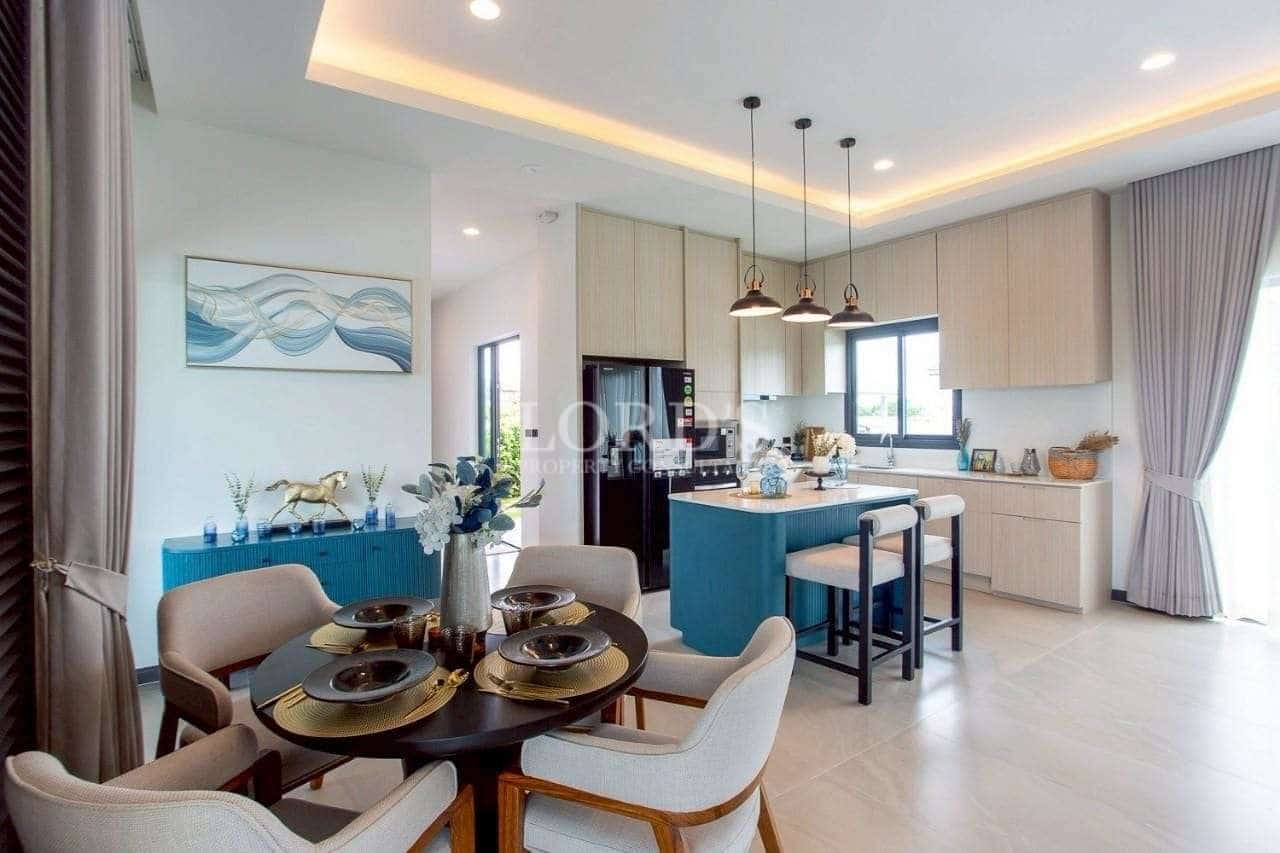 Open-plan kitchen and dining area with central island, pendant lighting, and modern furnishings.