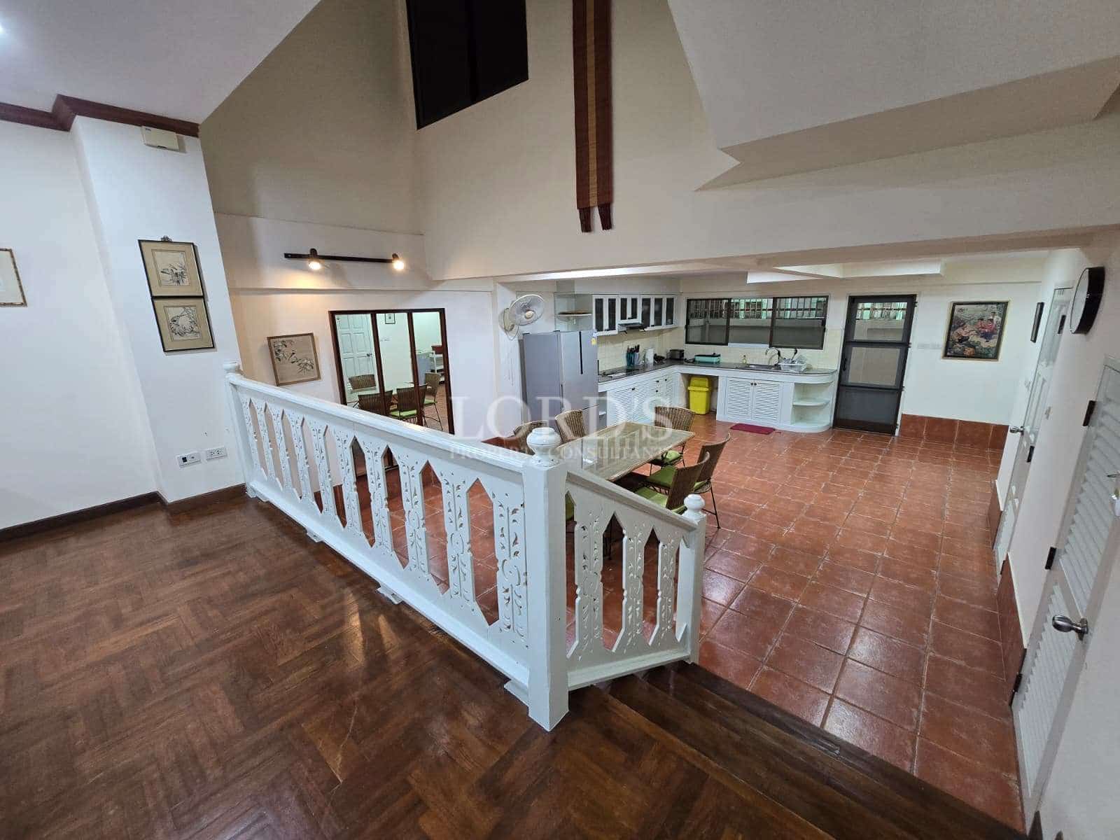 Open mezzanine level overlooking dining area and kitchen with terracotta tile flooring.