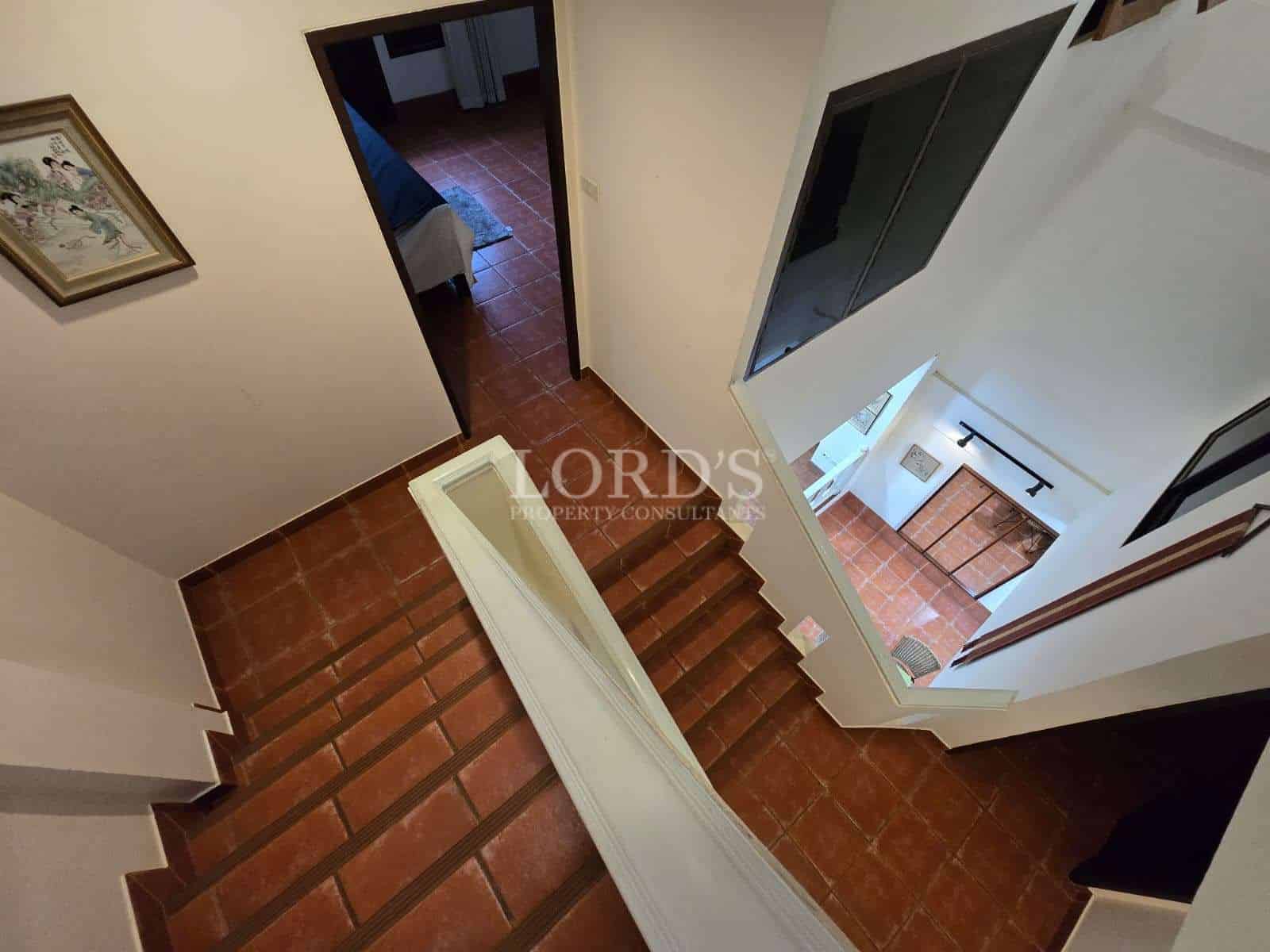 Interior staircase with terracotta tile steps and landing, viewed from upper floor.