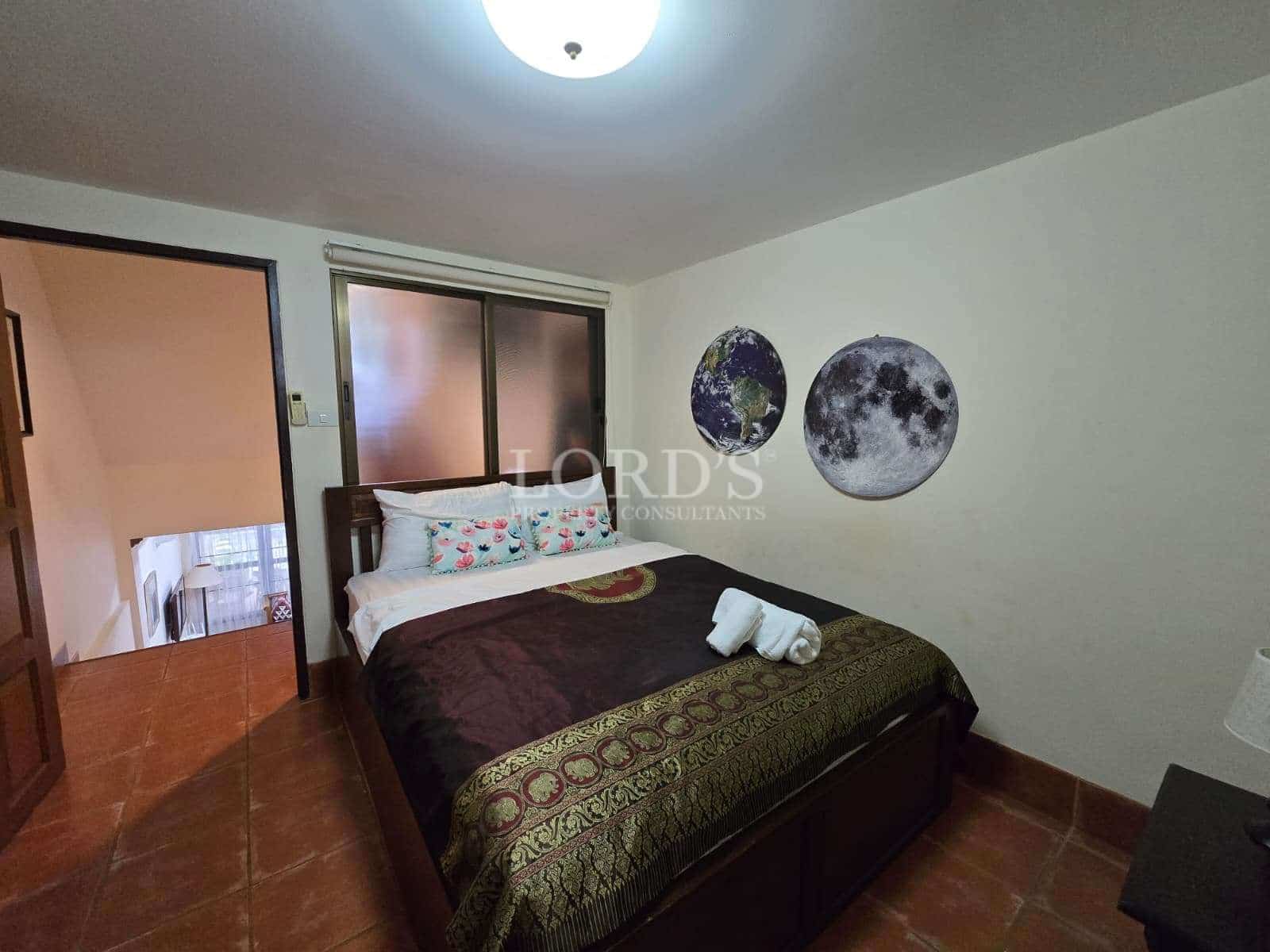Cozy bedroom with double bed, tiled flooring, wall art, and frosted sliding window.