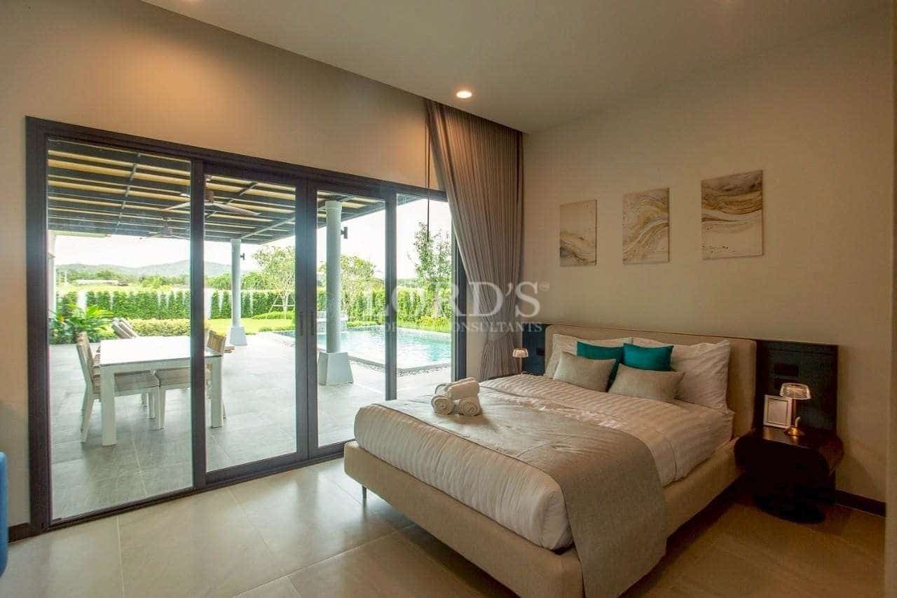 Bright bedroom with direct pool access, sliding glass doors, and modern upholstered bed.