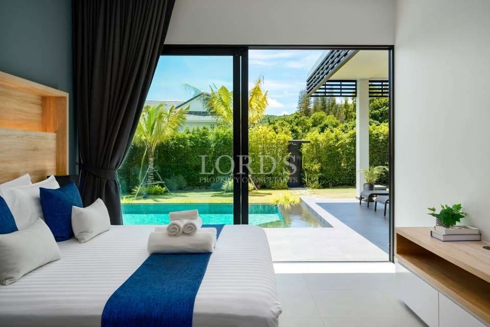 Modern bedroom with sliding glass doors opening to a private swimming pool and lush garden view.