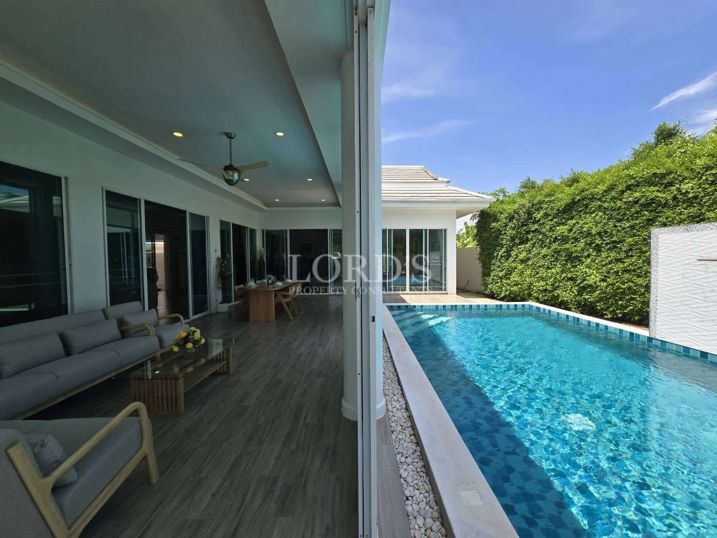 Luxury villa patio with seating area overlooking a private swimming pool and landscaped garden.