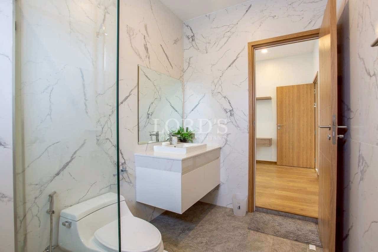 Modern bathroom with marble walls, glass shower, and floating vanity.