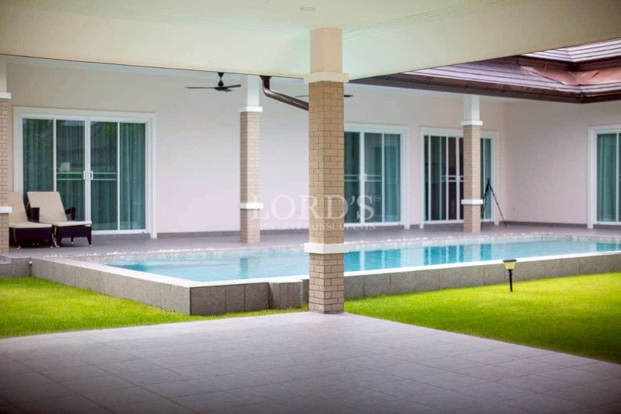 Covered poolside terrace with private swimming pool and landscaped lawn.