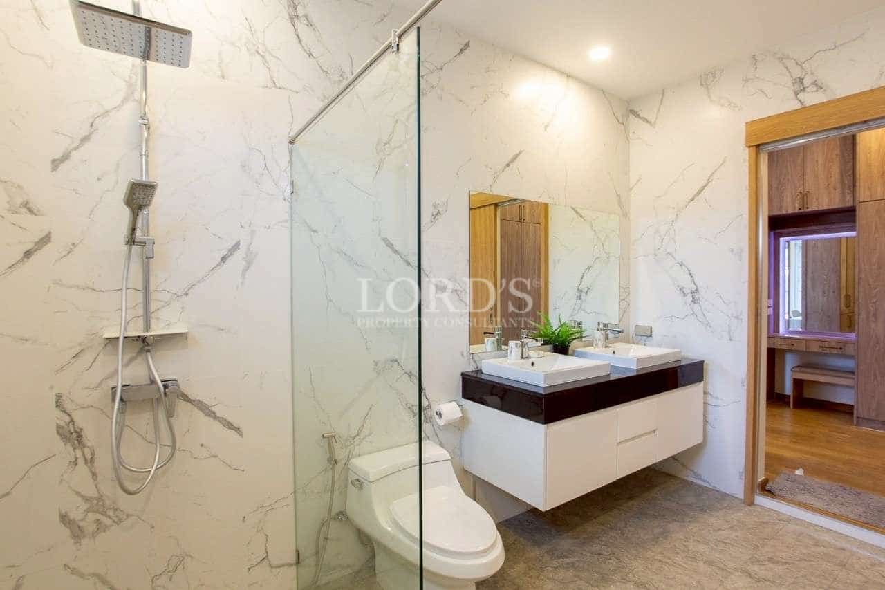 Modern bathroom with marble-style walls, glass shower enclosure, and floating double vanity.