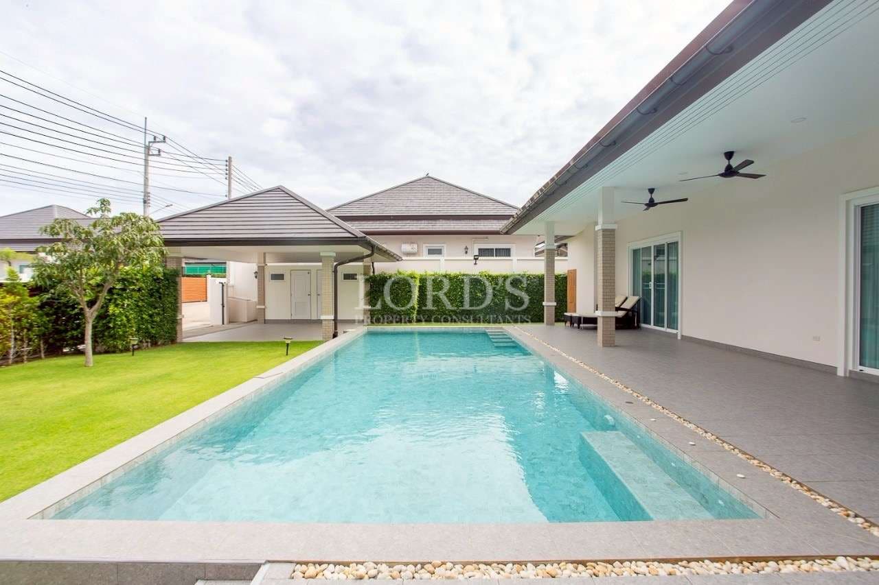 Modern single-story villa with a private swimming pool, covered patio, ceiling fans, and landscaped garden.