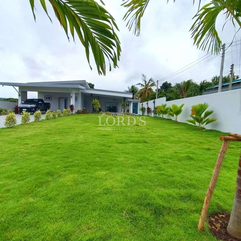 Spacious green lawn with modern single-story villa and landscaped garden