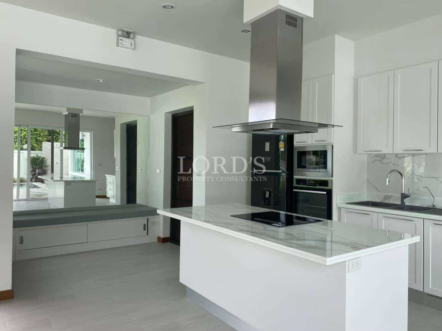 Modern kitchen with white cabinetry, marble-look countertops, kitchen island, built-in appliances, and stainless steel range hood.