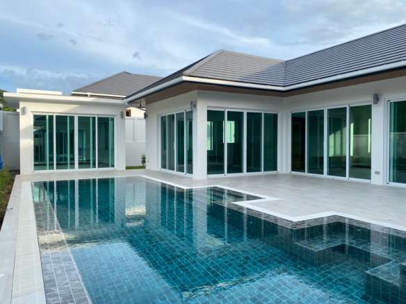 Modern luxury villa with a private swimming pool, large glass doors, and a spacious poolside terrace.