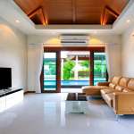 Modern living room with leather sofa, wood ceiling, and sliding doors opening to private pool