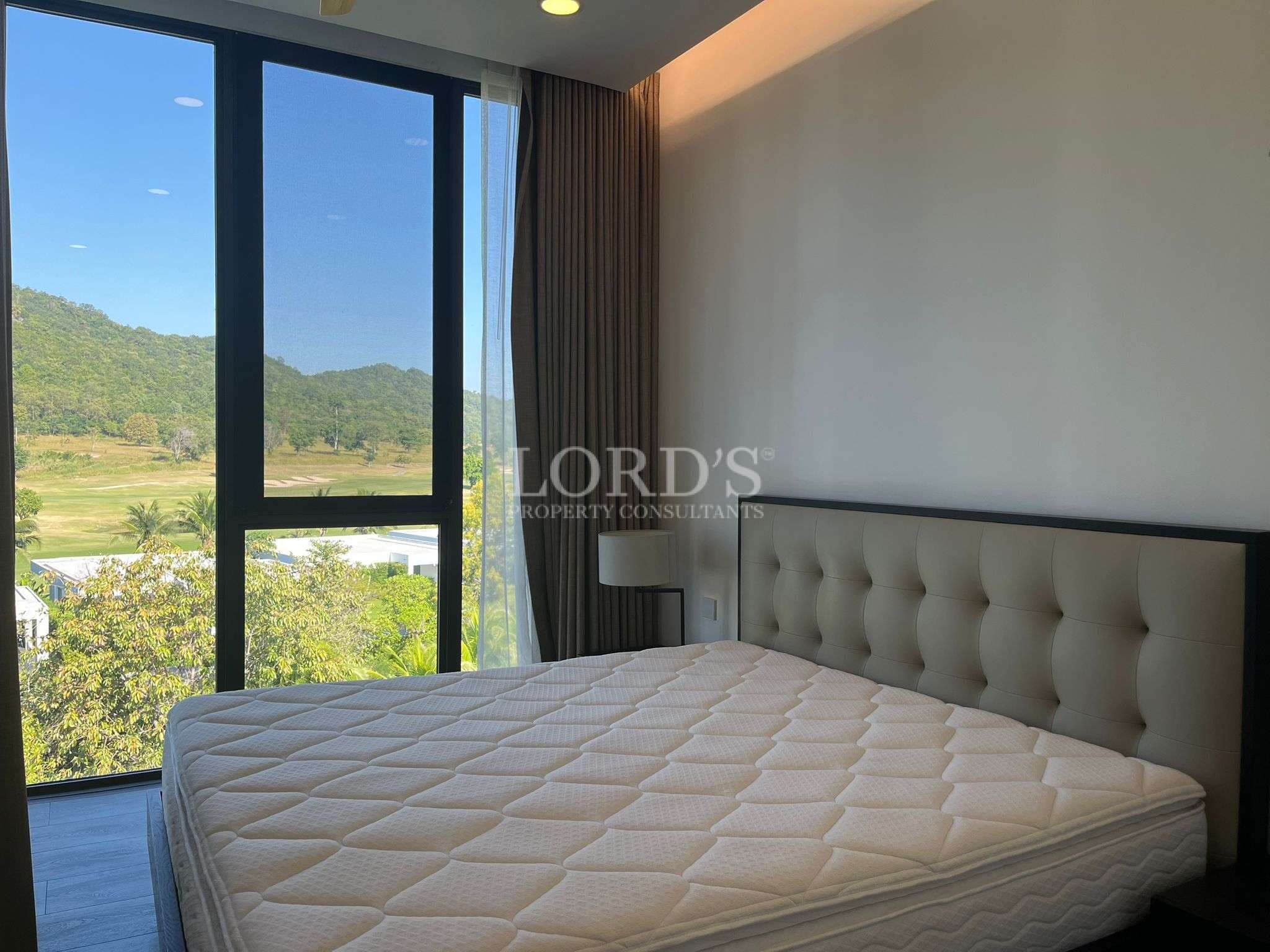 Modern bedroom with large window offering mountain and green landscape views