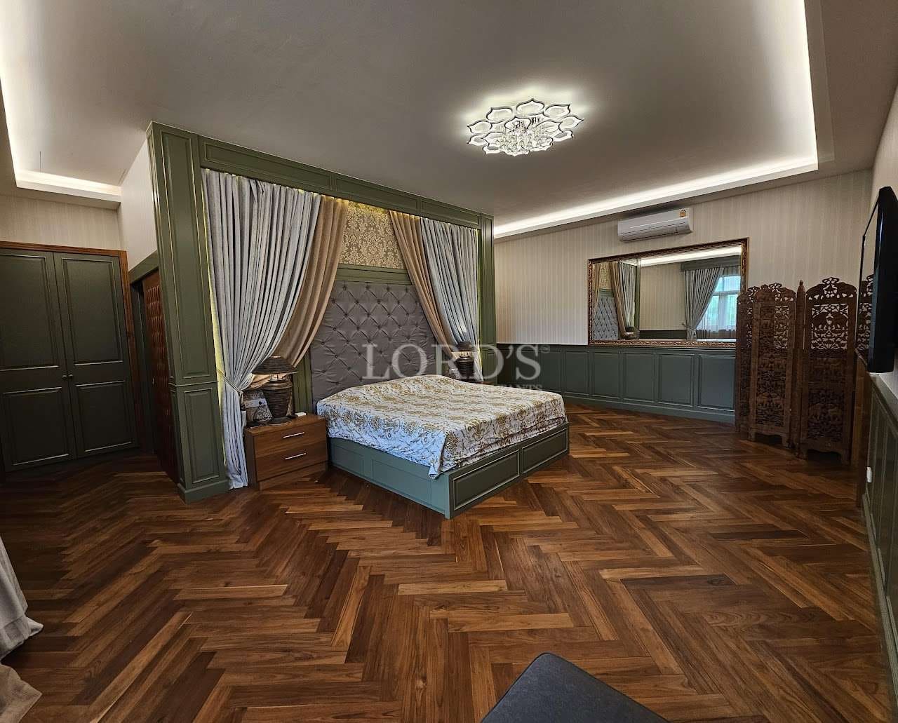 Spacious luxury bedroom with custom canopy bed, herringbone wooden flooring, ambient ceiling lighting, and built-in cabinetry