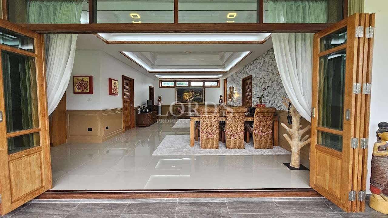 Elegant open-plan dining room with wooden folding doors, wicker dining chairs, recessed ceiling lighting, and glossy tiled flooring.