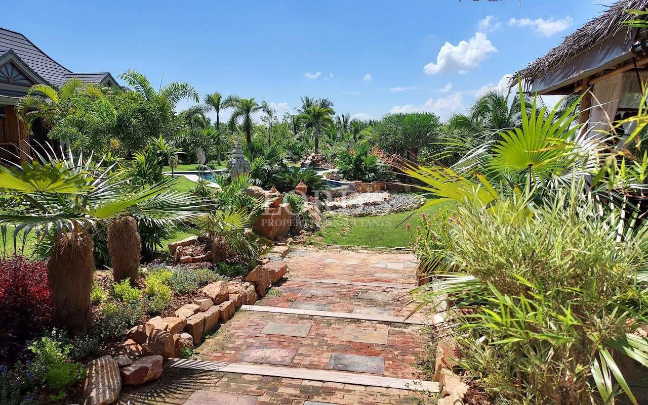 Stone garden pathway surrounded by lush tropical landscaping and palm trees in a private villa estate.