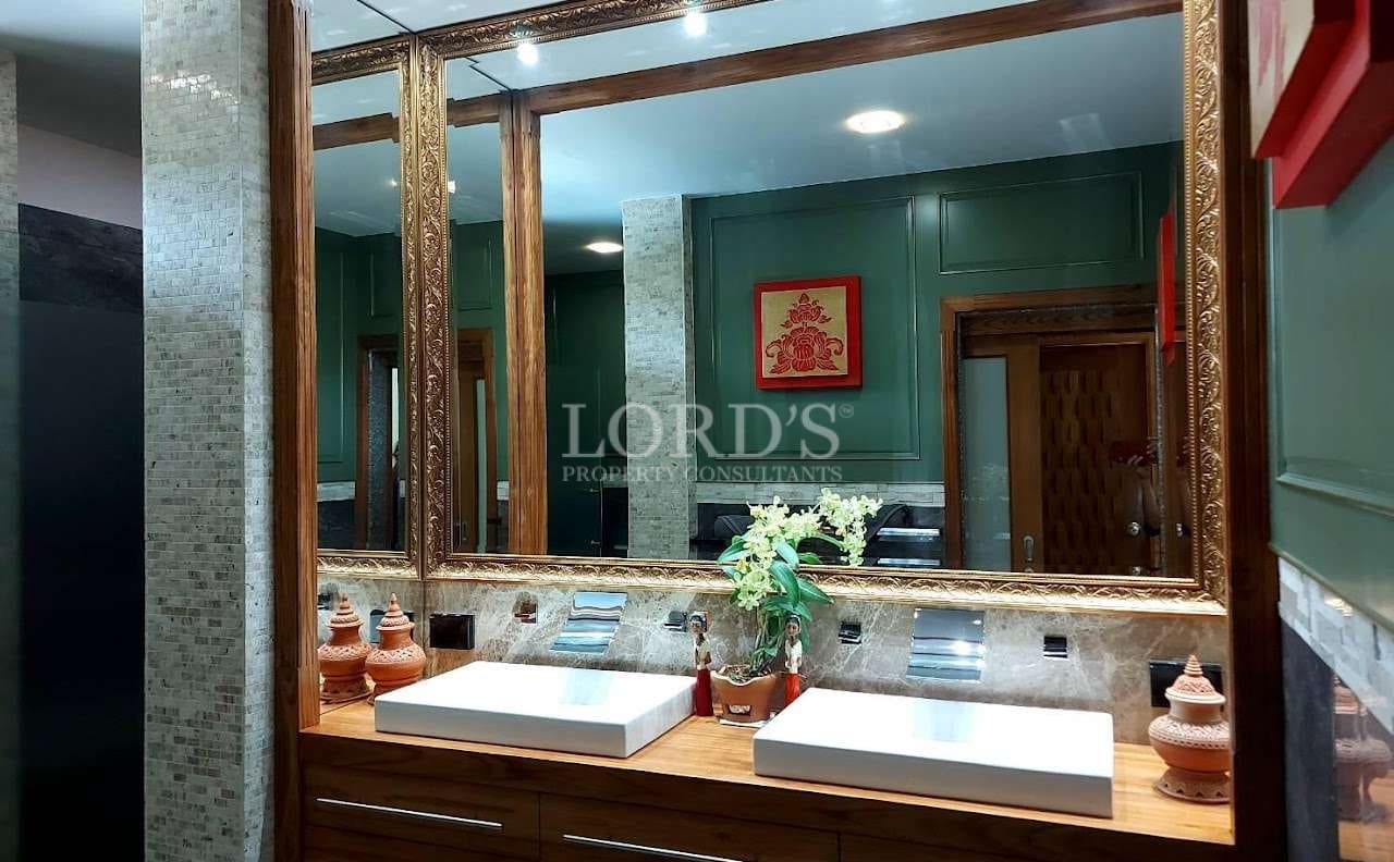 Luxury bathroom vanity with double vessel sinks, wooden countertop, gold-framed mirrors, textured wall tiles, and modern fixtures