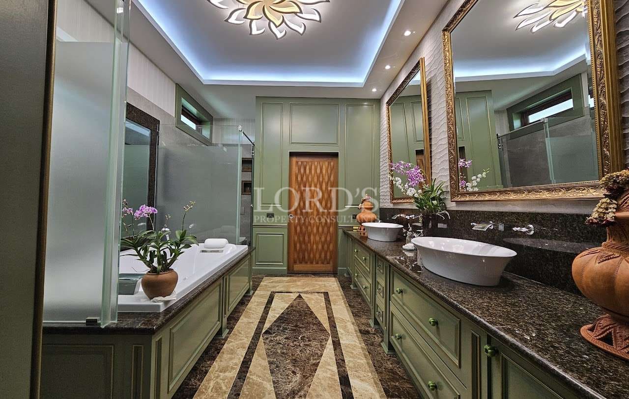 Luxury bathroom with double vanity, vessel sinks, jacuzzi bathtub, green cabinetry, stone flooring, and ambient ceiling lighting