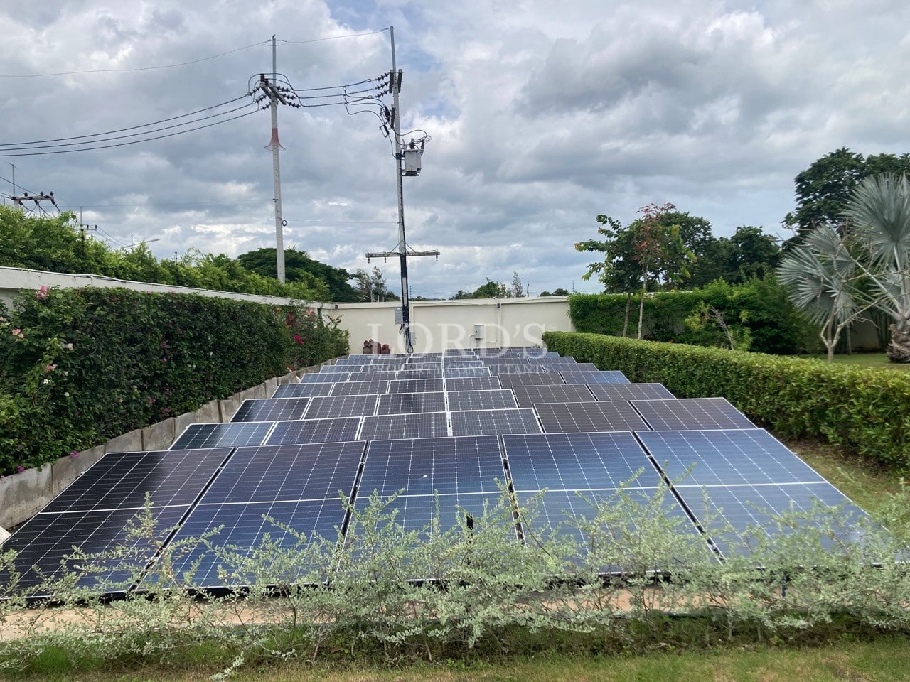 Ground-mounted solar panel system installed within a landscaped garden area of a private villa.