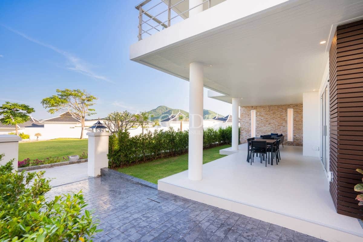 Covered outdoor terrace with dining area, garden view, and modern villa exterior.