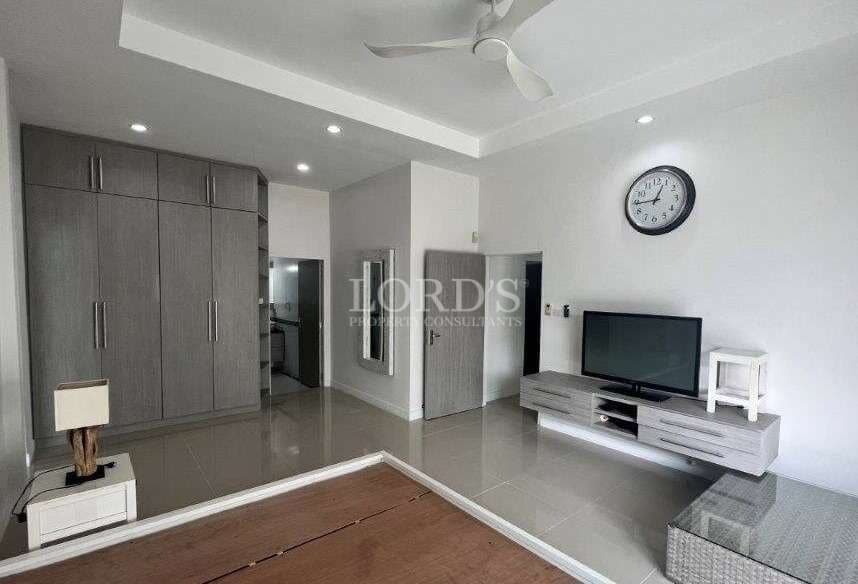 Modern bedroom with built-in wardrobe, wall-mounted TV, ceiling fan, glossy tiled floor, and minimalist décor
