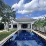 Luxury villa with long private swimming pool, tropical palm trees, white exterior, and blue sky