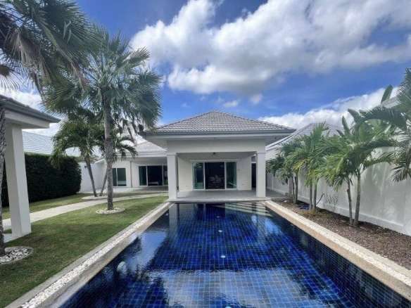 Luxury villa with long private swimming pool, tropical palm trees, white exterior, and blue sky