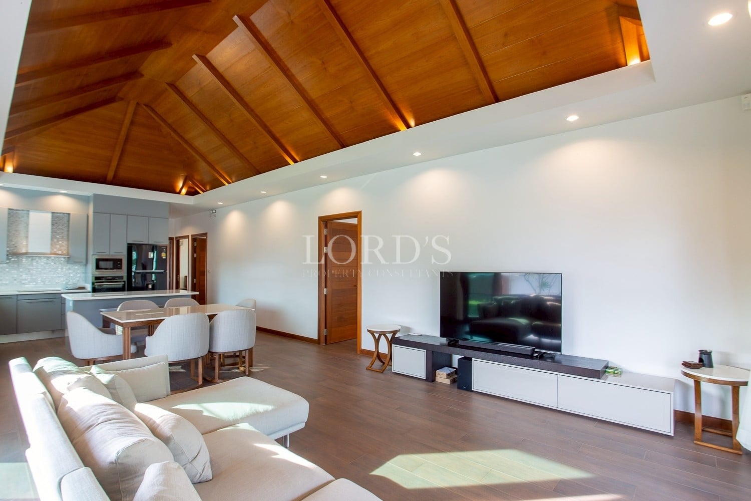 Spacious open-plan living and dining area with wooden ceiling and modern furnishings