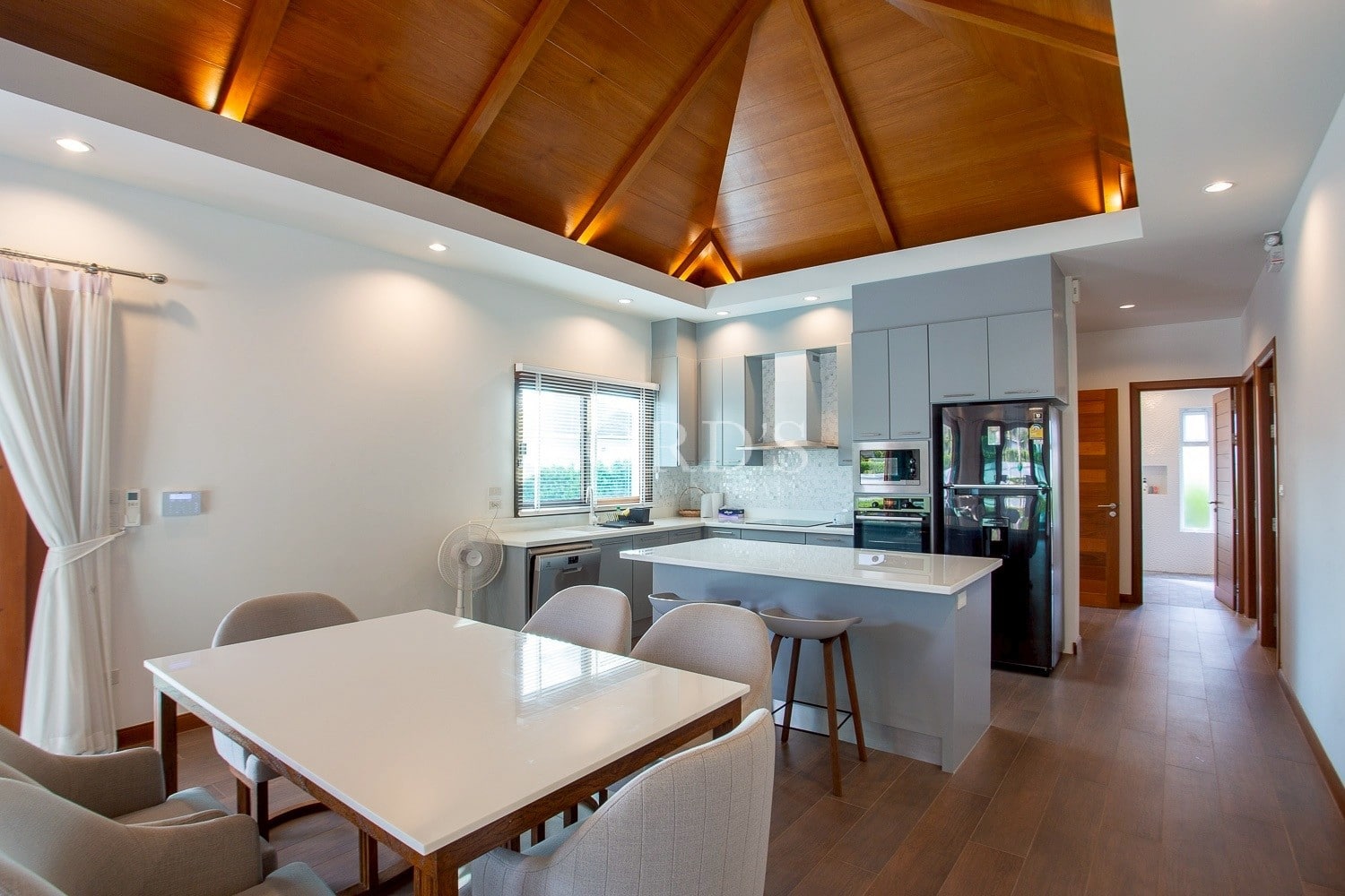 Modern open-plan kitchen and dining area with wooden ceiling and island counter