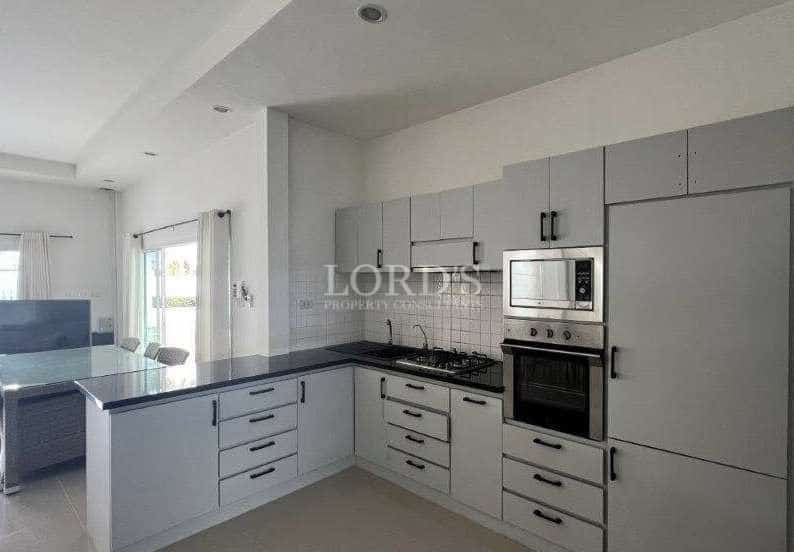 Modern L-shaped kitchen with light grey cabinets, black countertops, built-in oven and microwave, and open-plan layout