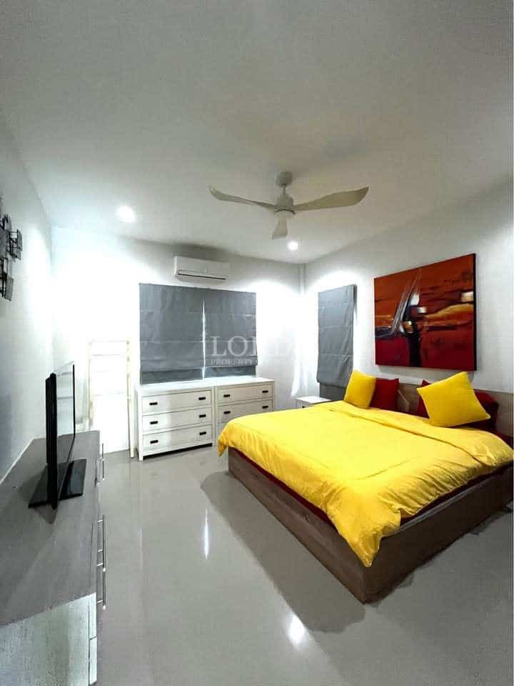 Modern bedroom with bright yellow bedding, ceiling fan, wall-mounted TV, glossy tiled floor, and contemporary décor