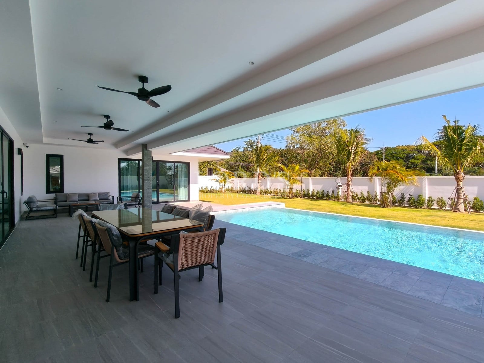Covered outdoor terrace with dining area, ceiling fans, private swimming pool, and landscaped garden.