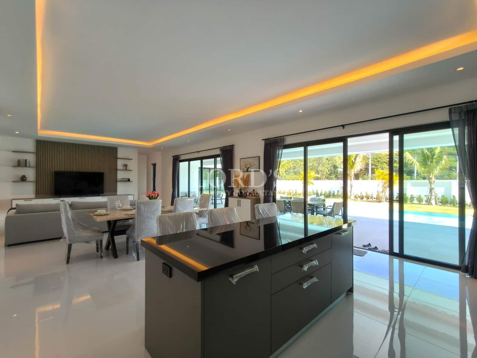 Open-plan kitchen and dining area with central island, ambient ceiling lighting, and sliding glass doors to the pool.