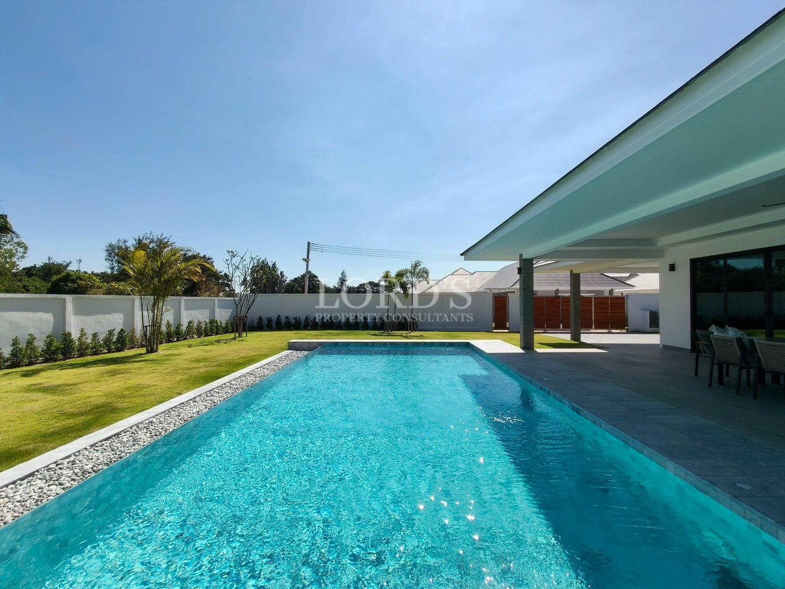Private swimming pool with landscaped garden, covered terrace, and modern villa exterior.