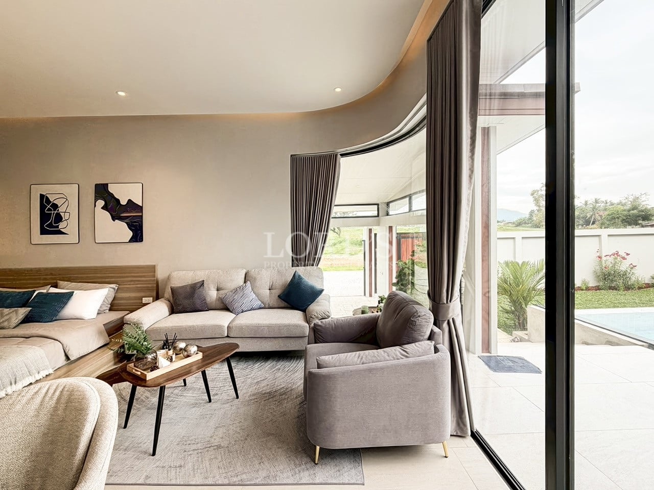 Modern living room with curved ceiling design, plush seating, large glass doors, and indoor-outdoor garden view.