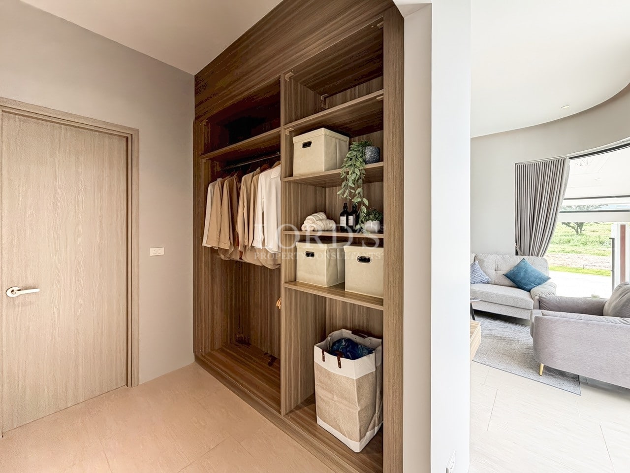 Built-in wooden wardrobe with open shelving, hanging clothes, fabric storage bins, and minimalist interior design.