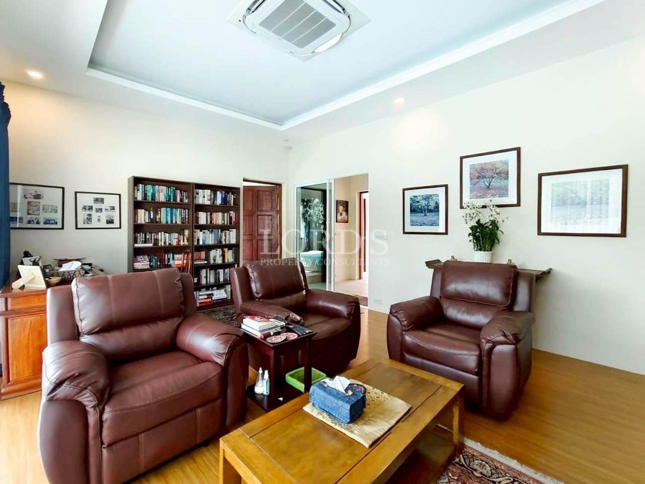 Cozy home library and sitting area with leather armchairs, wooden coffee table, and built-in bookshelf.
